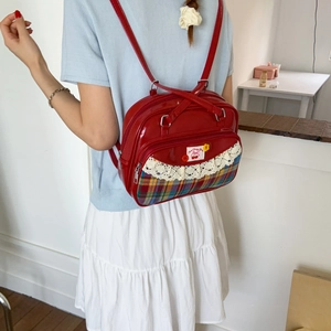 Detail of red patent leather backpack with cherry embroidery and lace plaid pocket