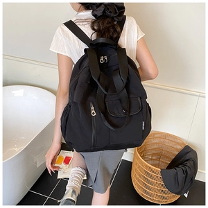 Detailed view of lightweight black nylon backpack with multi-pockets on a female model