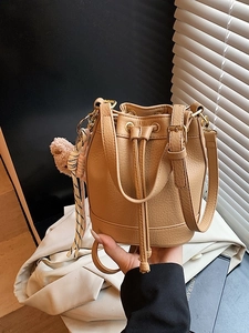 Light brown pebbled leather bucket bag with gold hardware and a cute teddy charm