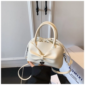 Gros plan du sac seau crème en PU avec nœud décoratif et pendentif en cœur