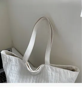 Detail of white pleated tote bag showing vertical texture and durable shoulder straps