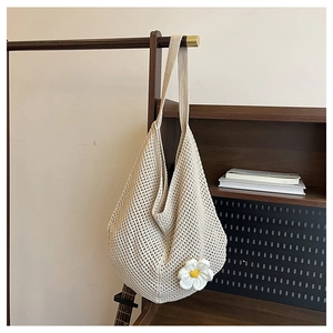 Détail du motif en maille tricotée sur un sac beige avec une fleur 3D blanche brodée