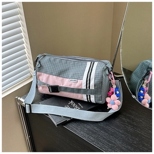 Détail latéral du sac bandoulière en nylon à carreaux gris et rose avec pendentif fleur