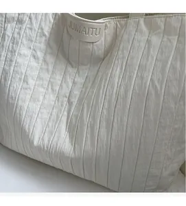 Detail of off-white tote bag showing pleated texture and leather JUMAITU logo patch