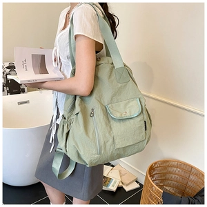 Sage green nylon travel tote bag showing multi-pocket details and premium fabric texture