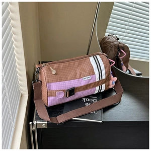 Détail du sac bandoulière en nylon à carreaux avec breloque fleur rose et étiquette latérale