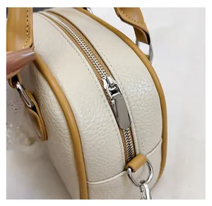 Macro detail of silver metal zipper on cream lychee pattern leather Boston bag