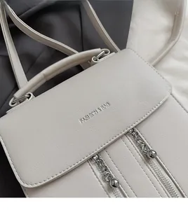 Gros plan détaillé du sac en cuir beige avec zips argentés et gravure de mode