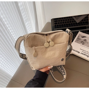 Detail of beige canvas crossbody bag featuring contrasting SJCHAO lettered shoulder strap