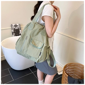 Detail view of grass green travel backpack with multi-pocket design and buckle flap