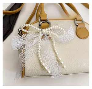 Detail of elegant pearl lace bow bag charm with white beads and silver metal clasp