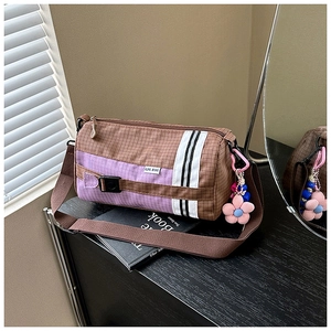 Détail du sac polochon en nylon à carreaux avec étiquette GPL et breloque fleurie