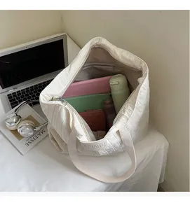 Spacious interior of beige quilted tote bag holding laptop, tablet, and water bottle