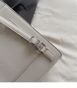 Gros plan d'un sac en cuir blanc avec boucle argentée et coutures de précision