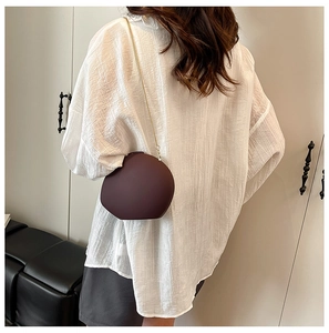 Détail d'un sac à bandoulière en acrylique rouge foncé avec chaîne dorée sur un modèle