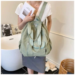 Light green nylon backpack featuring front zipper pockets and side storage compartments