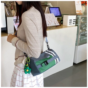 Détail du sac bandoulière en nylon à carreaux avec boucle et pendentif fleur verte