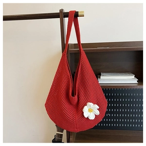 Gros plan d'un sac cabas rouge crocheté à la main avec une grande marguerite blanche