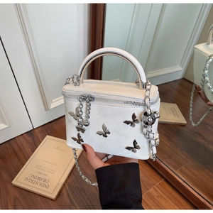 Detail of white box bag with 3D silver metal butterflies and arched metal handle