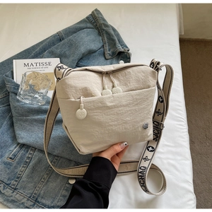 Detail of a cream canvas crossbody bag with jacquard logo strap and zipper pocket