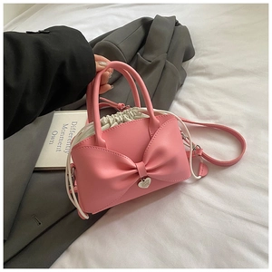 Détail d'un sac en cuir rose avec nœud, pendentif cœur et doublure à cordon blanc