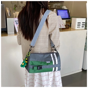 Détail du sac bandoulière en nylon à carreaux avec pendentif tournesol et bande de sport