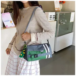 Détail du sac cylindre en nylon à carreaux avec breloque tournesol et sangle rayée