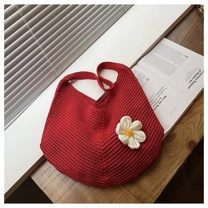 Détail du sac cabas en tricot ajouré rouge avec breloque fleurie sur bois