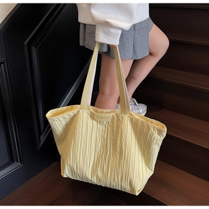 Detail of light yellow pleated tote bag with JUMAITU leather patch on wooden stairs