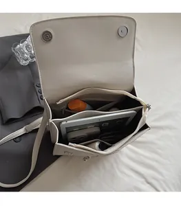 Vue détaillée du compartiment multiple et de la poche zippée dans un sac à main en cuir beige