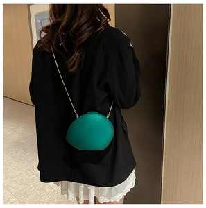 Sac bandoulière en acrylique vert foncé en forme de galet avec une fine chaîne dorée