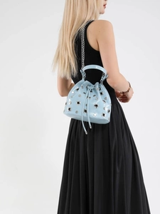 Light blue patent leather bucket bag with silver studs and chain strap on a model