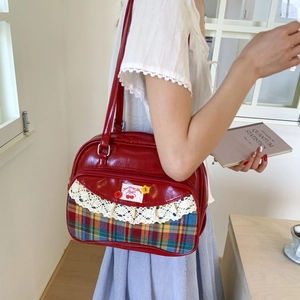 Detail of red leather tote bag with plaid pocket and white lace trim accents