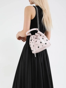 Pale pink bucket bag with silver studs and chain strap shown on model's shoulder