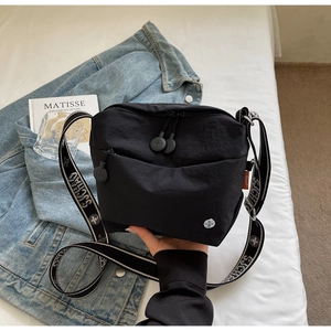 Detail of nylon crossbody bag with wide adjustable strap featuring artistic floral prints