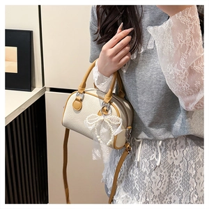 Detail of lychee textured leather mini boston bag with contrast strap and pearl lace bow