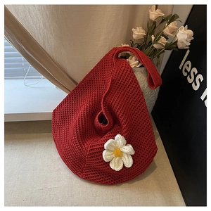 Gros plan détaillé d'un sac cabas tissé rouge orné d'une fleur blanche en tricot