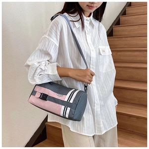 Détail d'un sac polochon en nylon à carreaux rose et gris avec bandoulière réglable