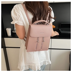 Detail of light pink pebbled leather backpack with metallic charms and fashion logo