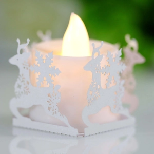 Detail of LED candle with laser-cut reindeer and snowflake patterns on white paper sleeve