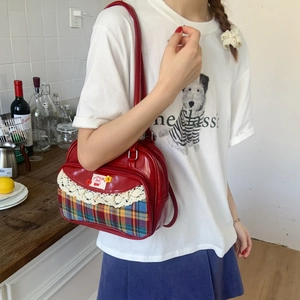 Detail of red leather tote bag featuring lace trim, plaid pattern and cherry patch