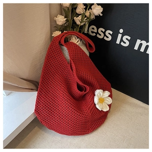 Détail du cabas rouge au crochet orné d'une marguerite blanche en tricot sur texture