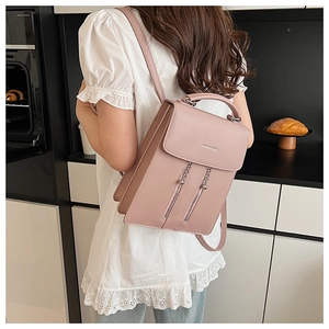 Detail of pink PU leather backpack featuring metal ball chains and top handle design
