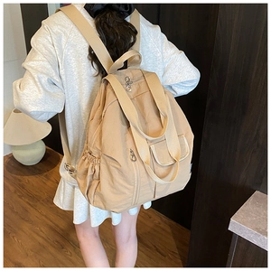 Detail view of khaki lightweight multi-pocket travel backpack showing storage and size on model