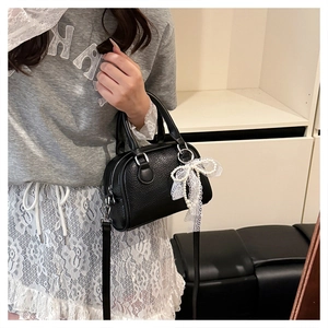 Detailed side view of a black lychee texture Boston bag with lace bow and pearl charm