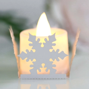 Close-up of white snowflake hollow decoration with a warm yellow LED candle light inside
