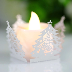 Gros plan d'une bougie LED avec abat-jour en papier découpé, motifs sapins et étoiles