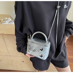Detailed view of silver bow-knot handbag with metal handle and chain strap on model