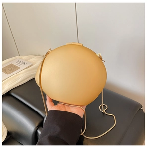 Détail de la pochette de soirée ovale en acrylique jaune avec chaîne dorée