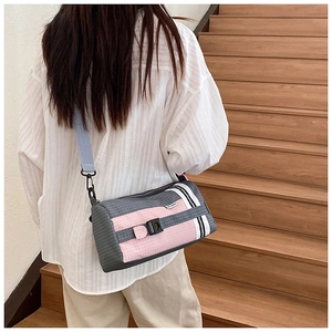 Détail du sac polochon en nylon à carreaux gris et rose avec bandoulière bleue